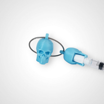 Two blue polylactic acid created using additive manufacturing skull cap clips on steel cable keyring. Featured attached to a syringe. Shown on a white background.