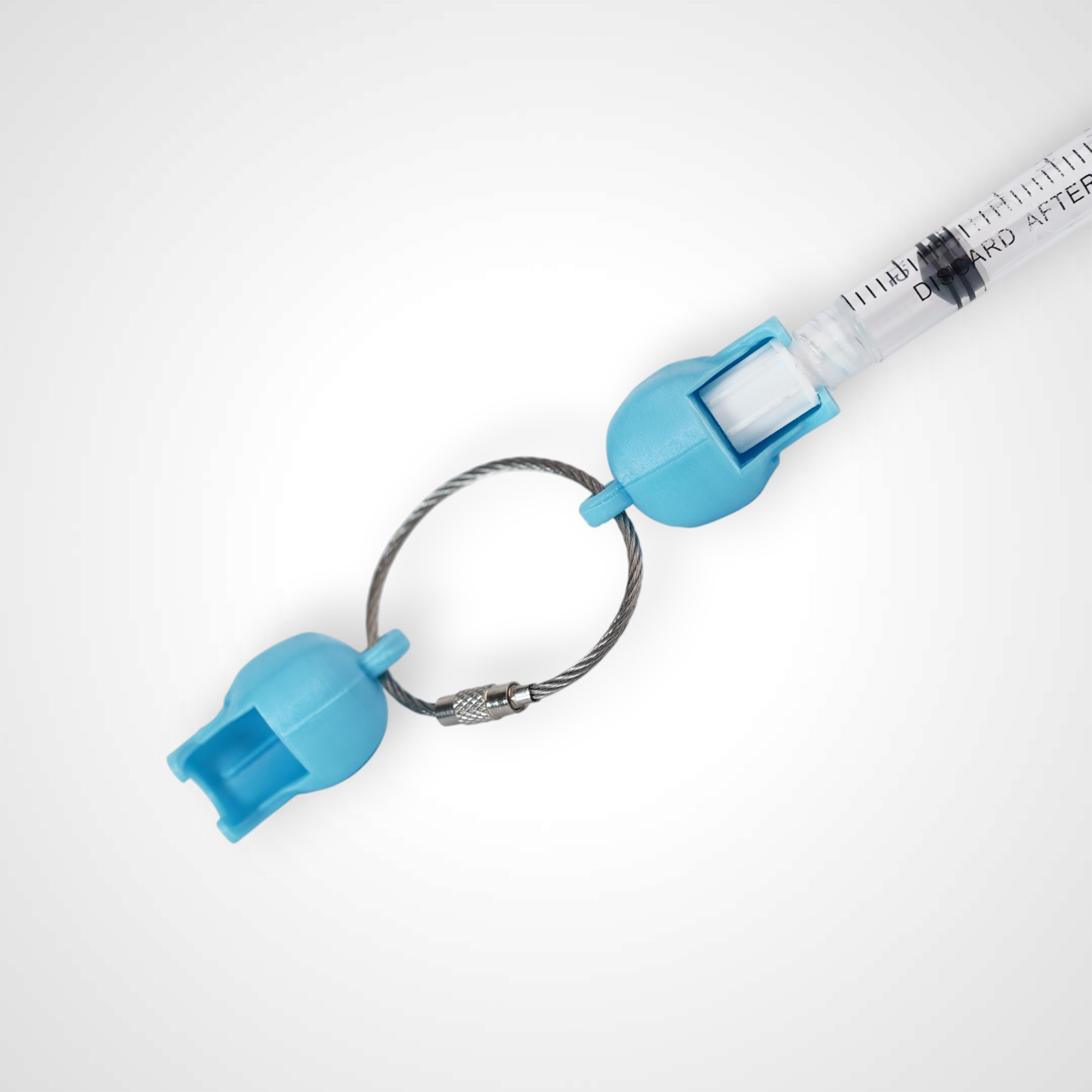 Two blue polylactic acid created using additive manufacturing skull cap clips on steel cable keyring. Featured attached to a syringe. Shown on a white background.