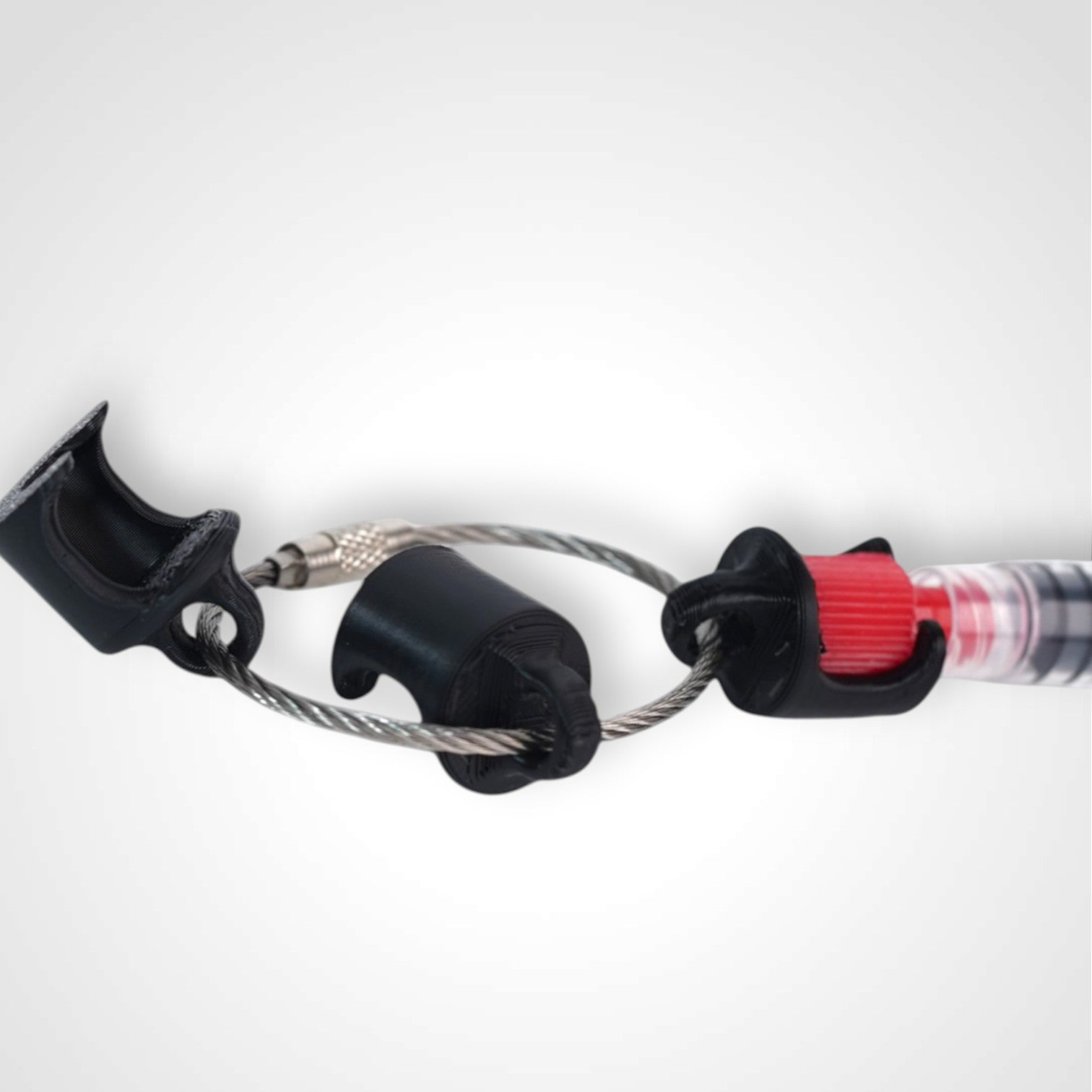 Black polylactic acid created using additive manufacturing B-Braun cap clip on steel cable keyring. Featured attached to a syringe. Shown on white background.