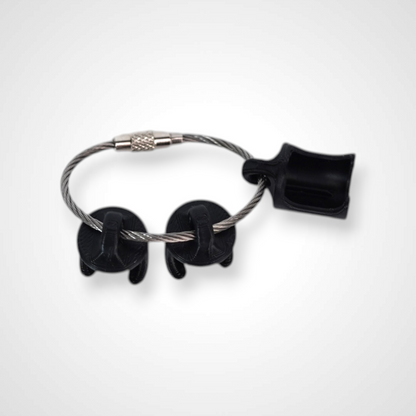 Three black polylactic acid created using additive manufacturing classic cap clips on steel cable keyring. Shown on a white background.