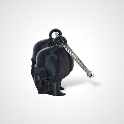 Two black polylactic acid created using additive manufacturing skull cap clips on steel cable keyring. Shown on a white background.