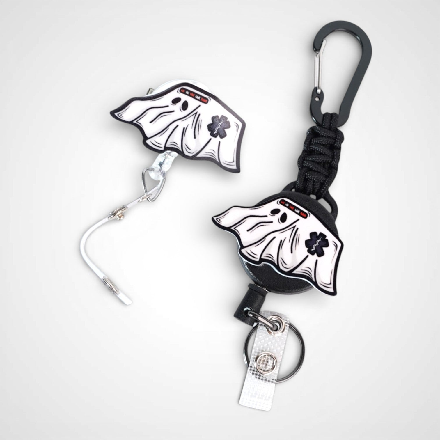 Ghost ambulance badge reel. On a swivel-alligator clip that rotates 360° with a nylon retractable string next to one on a carabiner with steel retractable cable. Shown on a white background.