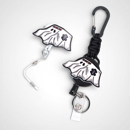 Ghost ambulance badge reel. On a swivel-alligator clip that rotates 360° with a nylon retractable string next to one on a carabiner with steel retractable cable. Shown on a white background.