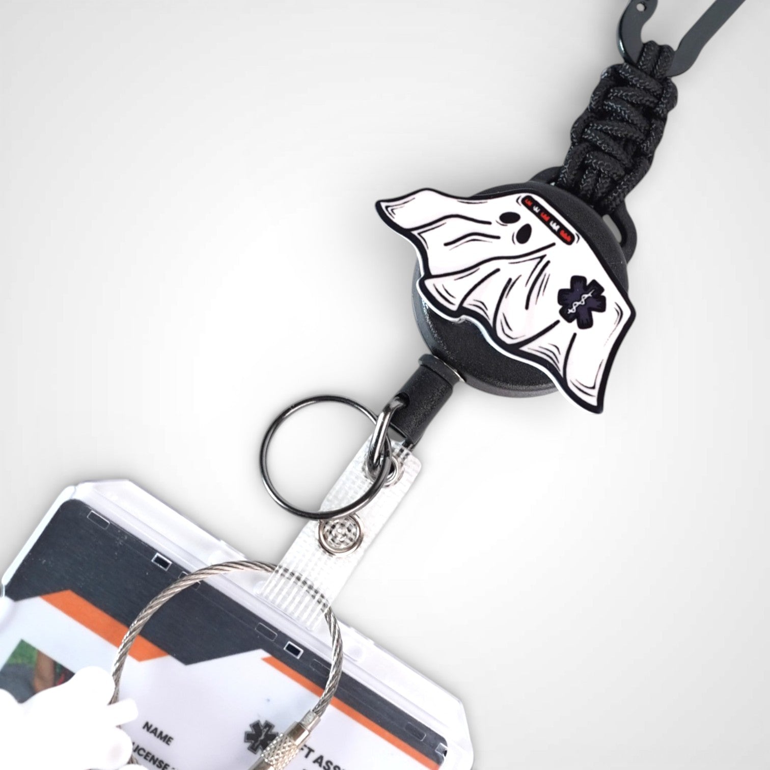 Ghost ambulance badge reel. On a carabiner with steel retractable cable. Shown on a white background.