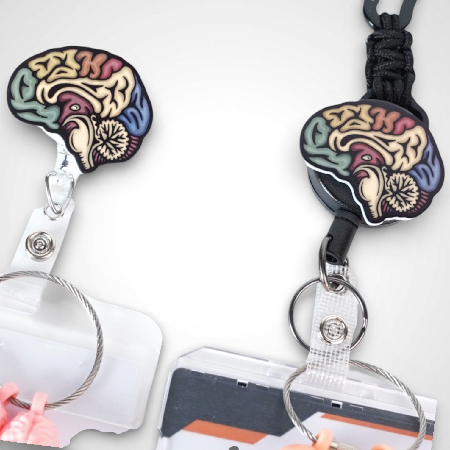 Sagittal brain badge reel. On a carabiner with a steel retractable cable next to a swivel-alligator clip that rotates 360° with a nylon retractable string. Shown on a white background. 