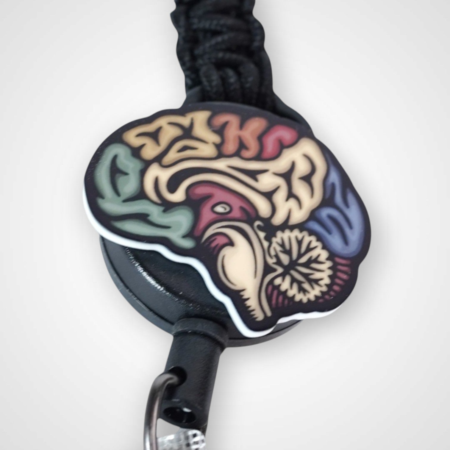 Sagittal brain badge reel. On a carabiner with a steel retractable cable. Shown on a white background.