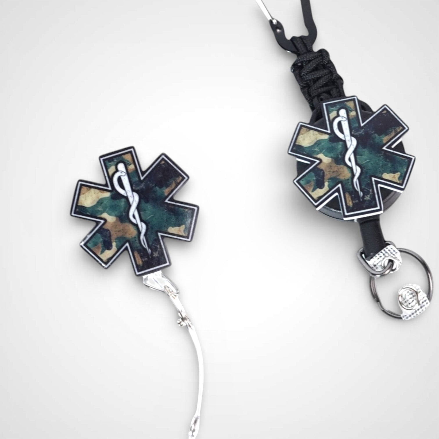 Camo Star badge reel. On a carabiner with a steel retractable cable next to a swivel-alligator clip that rotates 360° with a nylon retractable string. Shown on a white background. 