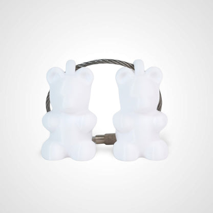 Two white polylactic acid created using additive manufacturing gummy bear cap clips on steel cable keyring. Shown on a white background.