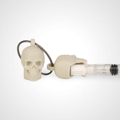 Two off white polylactic acid created using additive manufacturing skull cap clips on steel cable keyring. Featured attached to a syringe. Shown on a white background.