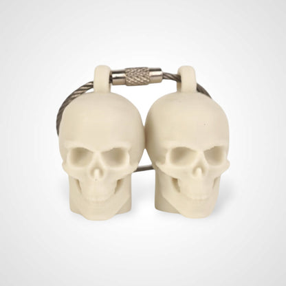 Two off white polylactic acid created using additive manufacturing skull cap clips on steel cable keyring. Shown on a white background.