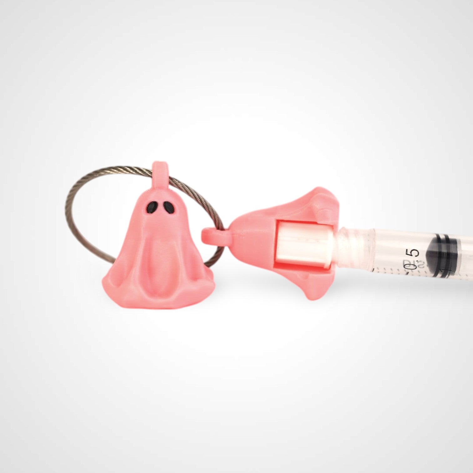 Two pink polylactic acid created using additive manufacturing ghost cap clips on steel cable keyring. Featured attached to a syringe. Shown on a white background.