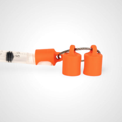 Three orange polylactic acid created using additive manufacturing classic cap clips on steel cable keyring. Featured attached to a syringe. Shown on a white background.