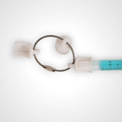 Three white polylactic acid created using additive manufacturing faux flush cap clip on steel cable keyring. Featured attached to a syringe. Shown on a white background.