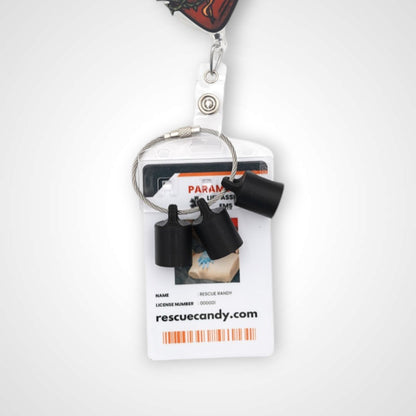 Three black polylactic acid created using additive manufacturing classic cap clips on steel cable keyring. Featured attached to a badge. Shown on a white background.