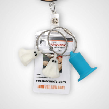 Two white polylactic acid created using additive manufacturing ghost cap clips on steel cable keyring. Featured attached to a badge. Shown on a white background.