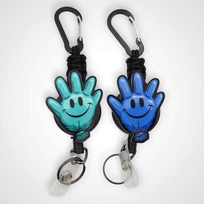 Teal and blue happy glove partner set badge reel. On a carabiner with a steel retractable cable. Shown on a white background.