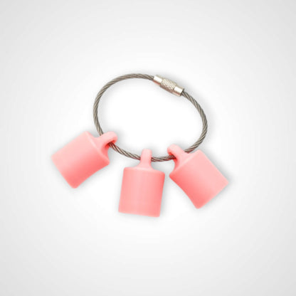 Three pink polylactic acid created using additive manufacturing classic cap clips on steel cable keyring. Shown on a white background.
