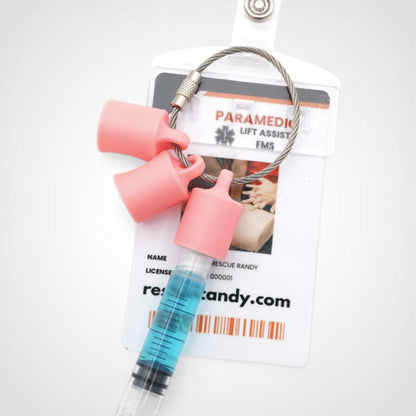 Three pink polylactic acid created using additive manufacturing classic cap clips on steel cable keyring. Featured attached to a syringe and on a badge. Shown on a white background.