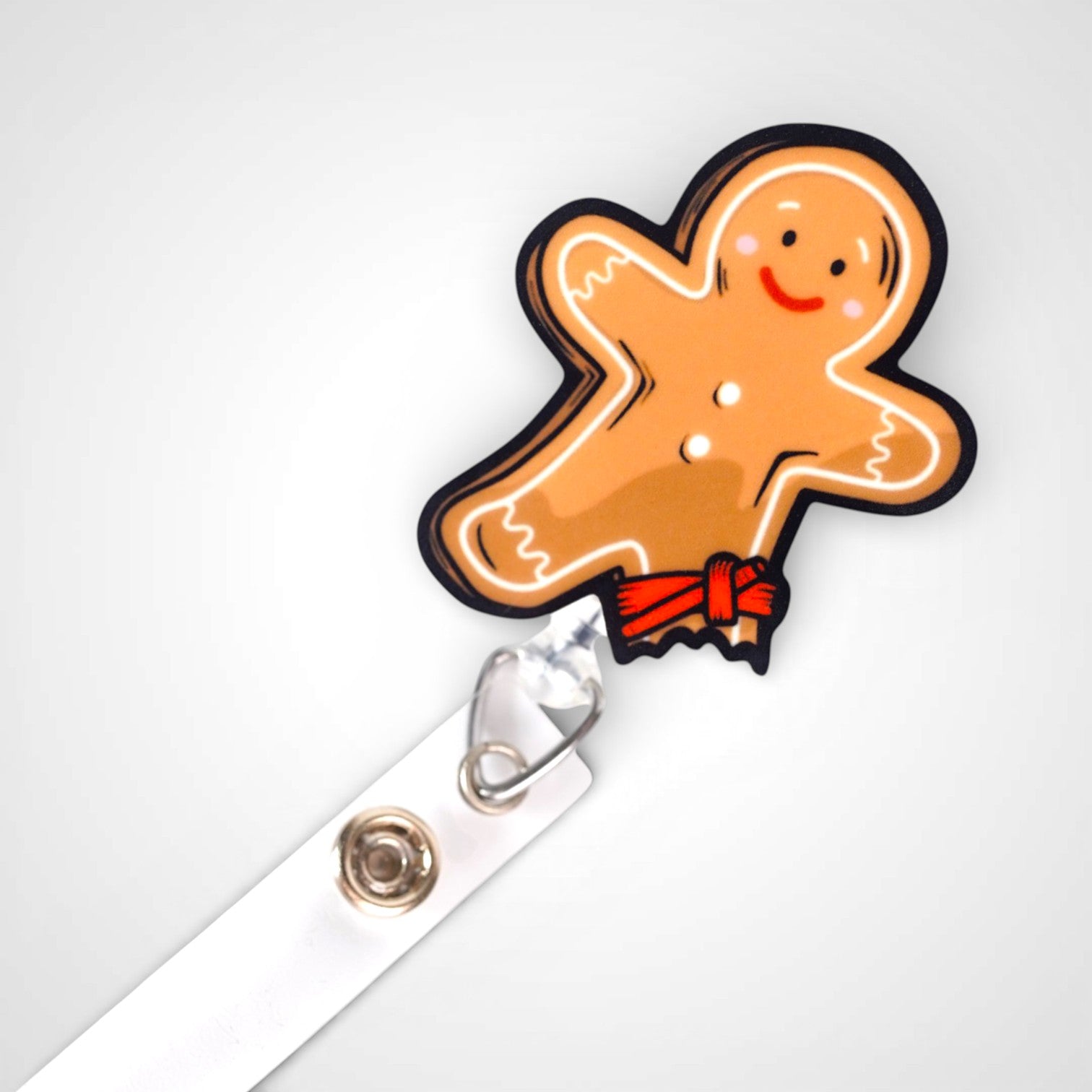Tourniquet gingerbread man badge reel. On a swivel-alligator clip that rotates 360° with a nylon retractable string. Shown on a white background.