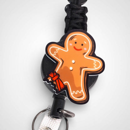 Tourniquet gingerbread man badge reel. On a carabiner with a steel retractable cable. Shown on a white background.
