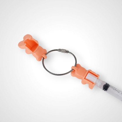 Two orange polylactic acid created using additive manufacturing gummy bear clips on steel cable keyring. Featured attached to a syringe. Shown on a white background.
