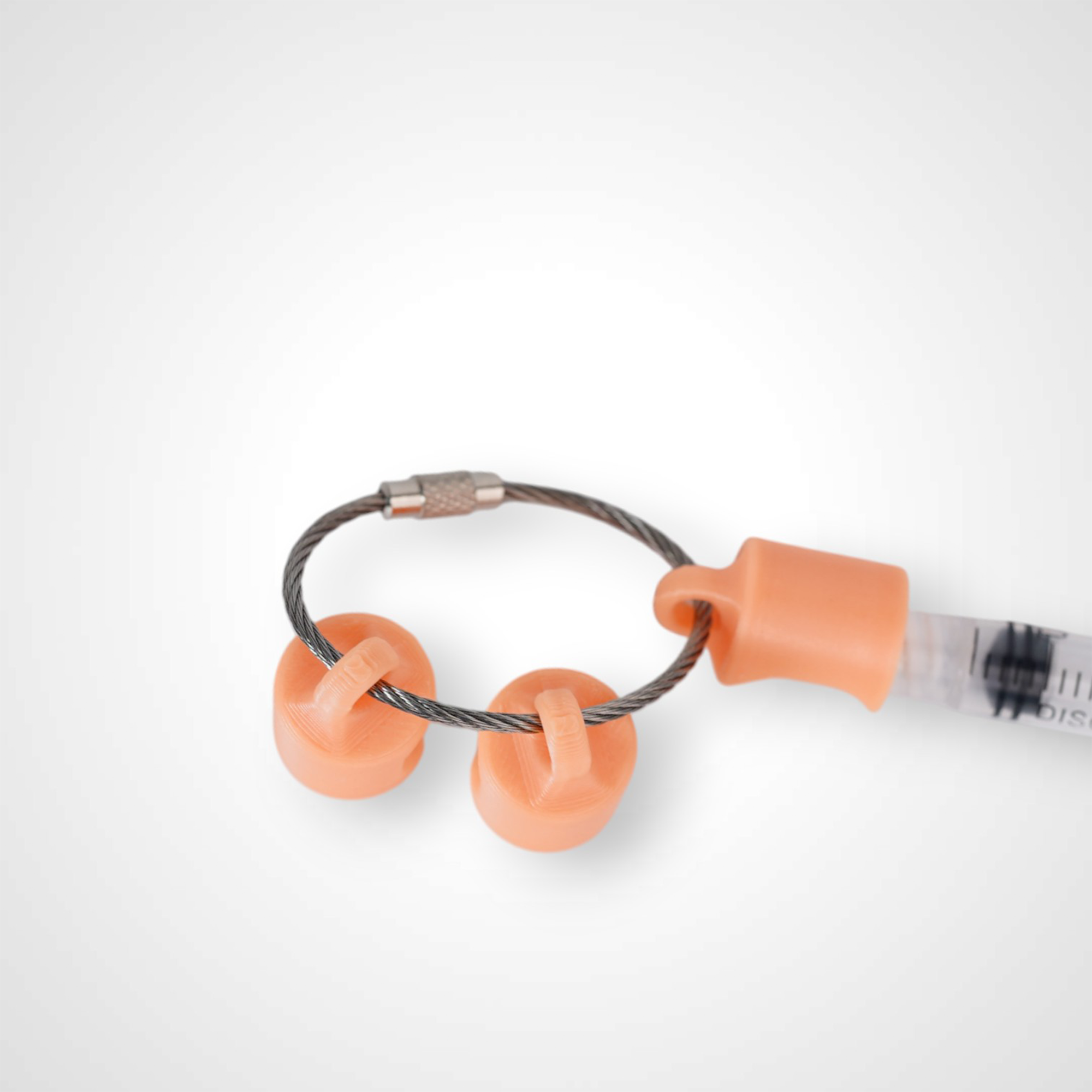 Three orange polylactic acid created using additive manufacturing classic cap clips on steel cable keyring. Featured attached to a syringe. Shown on a white background.