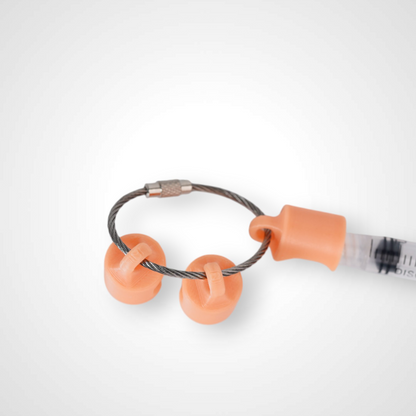 Three orange polylactic acid created using additive manufacturing classic cap clips on steel cable keyring. Featured attached to a syringe. Shown on a white background.