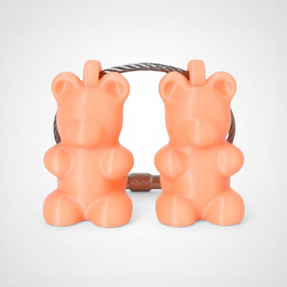 Two orange polylactic acid created using additive manufacturing gummy bear clips on steel cable keyring. Shown on a white background.