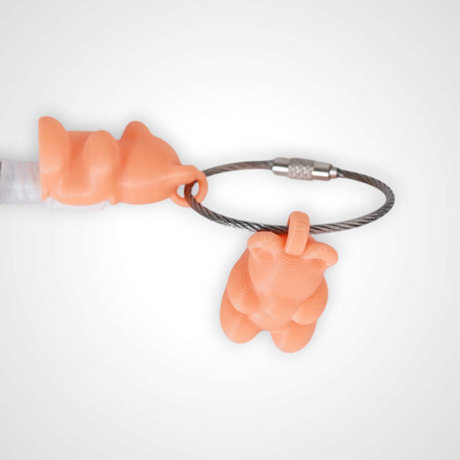 Two orange polylactic acid created using additive manufacturing gummy bear clips on steel cable keyring. Featured attached to a syringe. Shown on a white background.