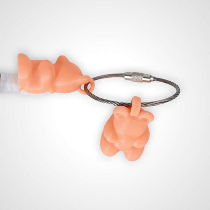 Two orange polylactic acid created using additive manufacturing gummy bear clips on steel cable keyring. Featured attached to a syringe. Shown on a white background.