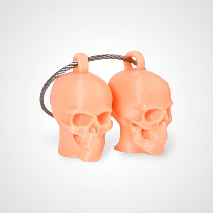 Two orange polylactic acid created using additive manufacturing skull cap clips on steel cable keyring. Shown on a white background.