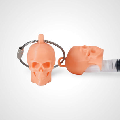 Two orange polylactic acid created using additive manufacturing skull cap clips on steel cable keyring. Featured attached to a syringe. Shown on a white background.