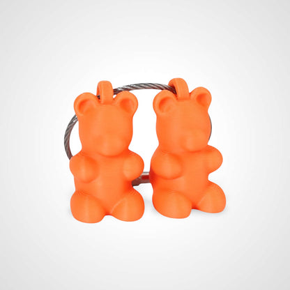 Two orange polylactic acid created using additive manufacturing gummy bear cap clips on steel cable keyring. Shown on a white background.