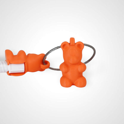 Two orange polylactic acid created using additive manufacturing gummy bear cap clips on steel cable keyring. Featured attached to a syringe. Shown on a white background.