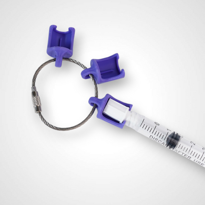 Three purple polylactic acid created using additive manufacturing classic cap clips on steel cable keyring. Featured attached to a syringe. Shown on a white background.
