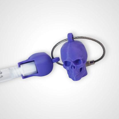 Two purple polylactic acid created using additive manufacturing skull cap clips on steel cable keyring. Featured attached to a syringe. Shown on a white background.