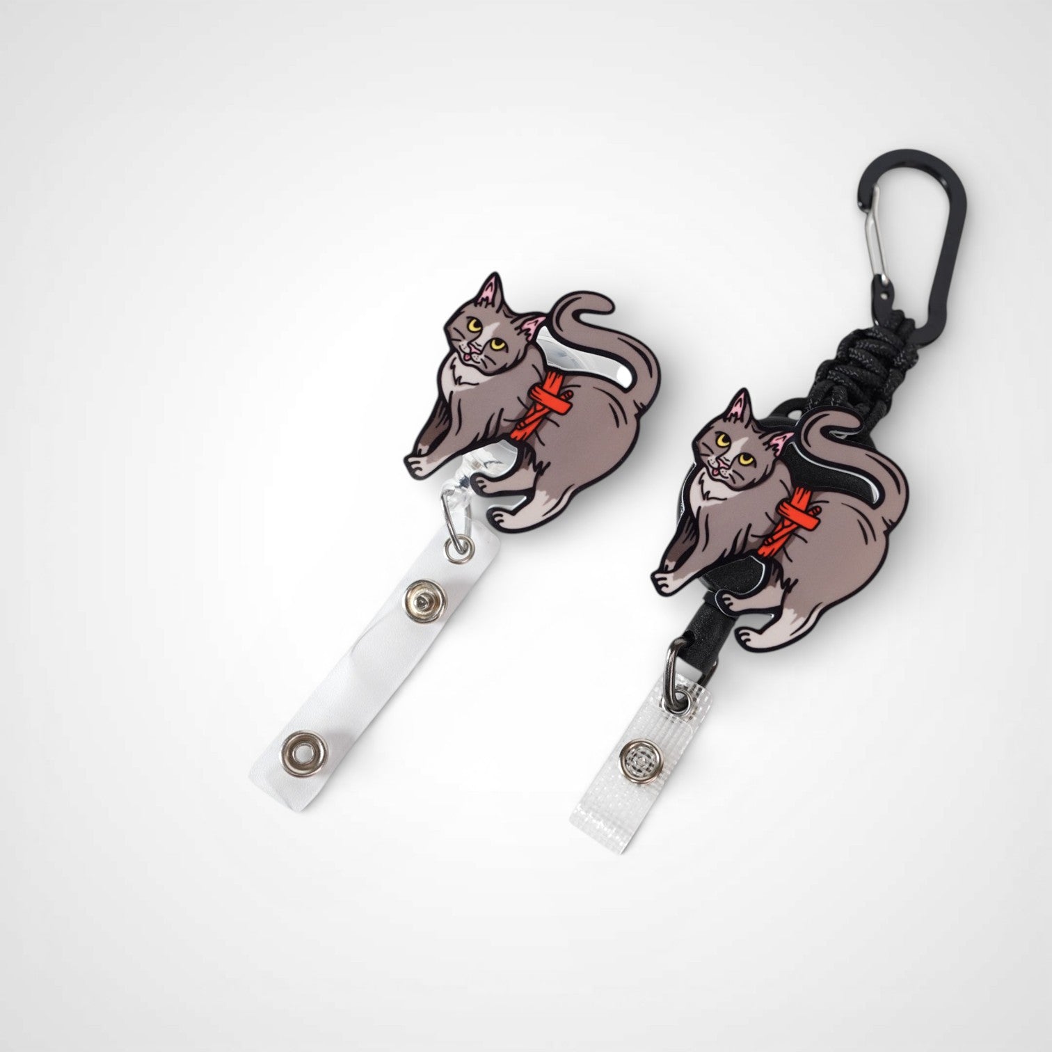 Tournicat badge reel. On a carabiner with a steel retractable cable next to a swivel-alligator clip that rotates 360° with a nylon retractable string. Shown on a white background. 
