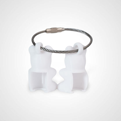 Two white polylactic acid created using additive manufacturing gummy bear cap clips on steel cable keyring. Shown on a white background.