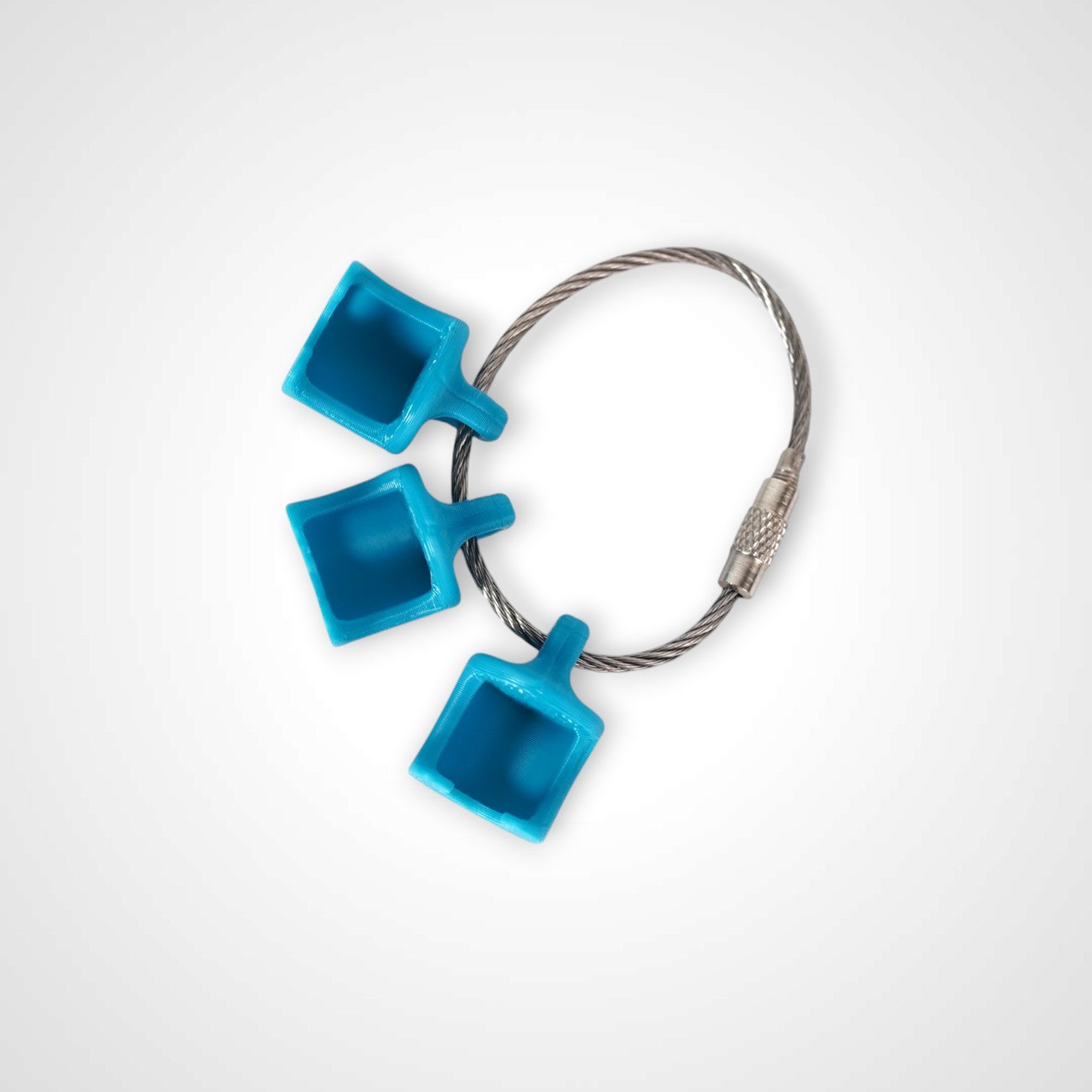 Blue polylactic acid created using additive manufacturing B-Braun cap clip on steel cable keyring. Shown on white background.