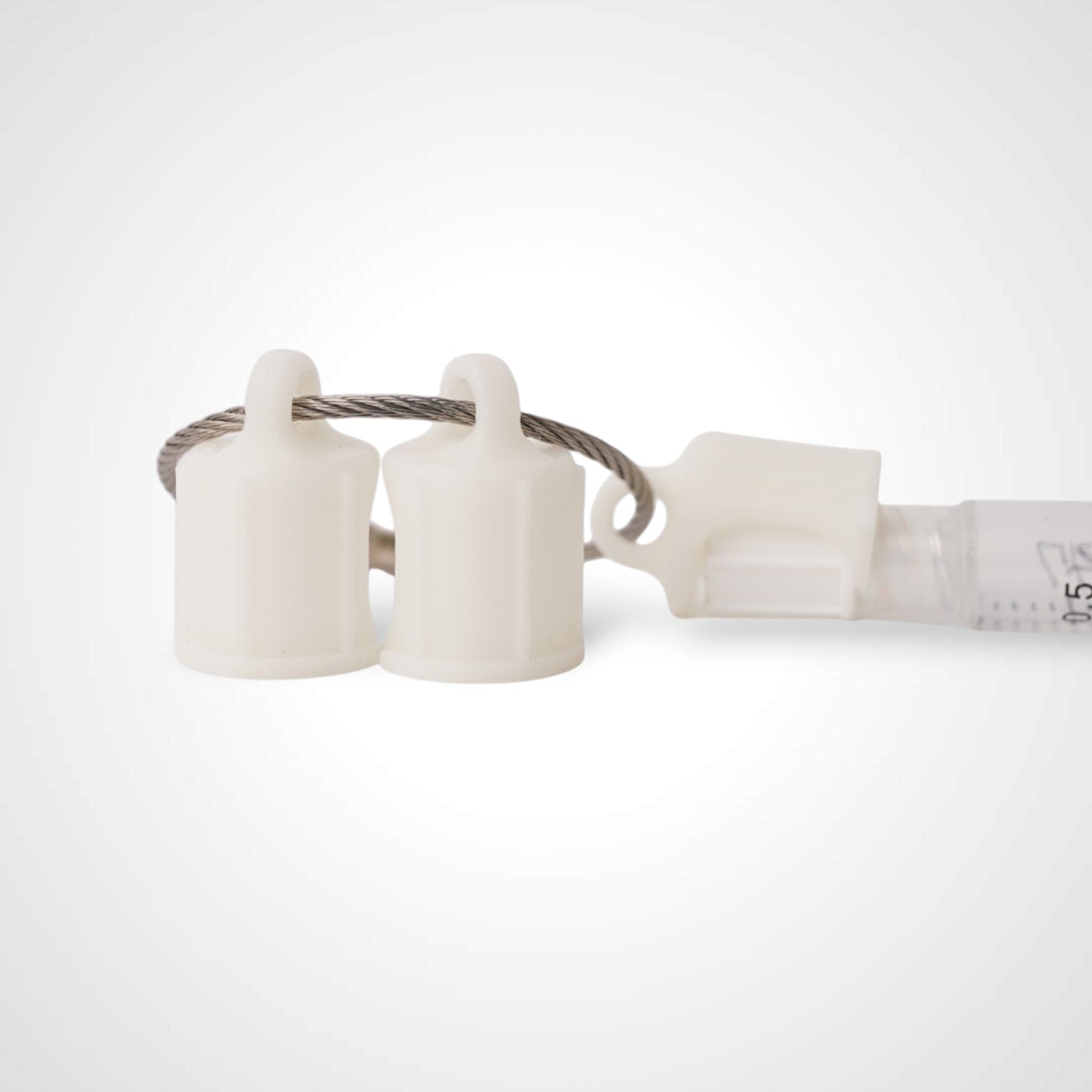 Three white polylactic acid created using additive manufacturing faux flush cap clips on steel cable keyring. Featured attached to a syringe. Shown on a white background.