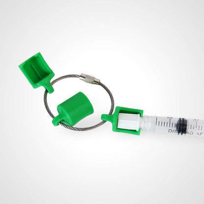 Three green polylactic acid created using additive manufacturing classic cap clips on steel cable keyring. Featured attached to a syringe. Shown on a white background.